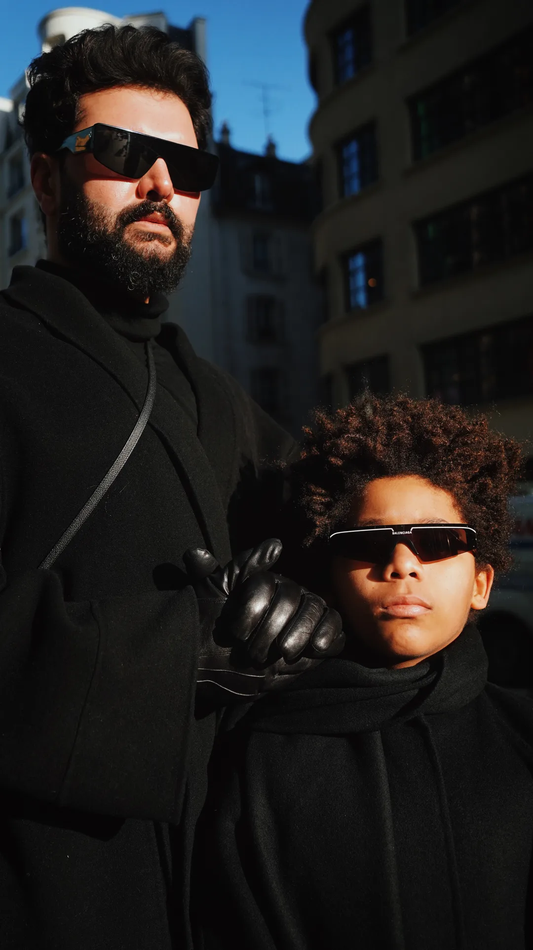 Editorial portrait of two people dressed in black with sunglasses on a city street
