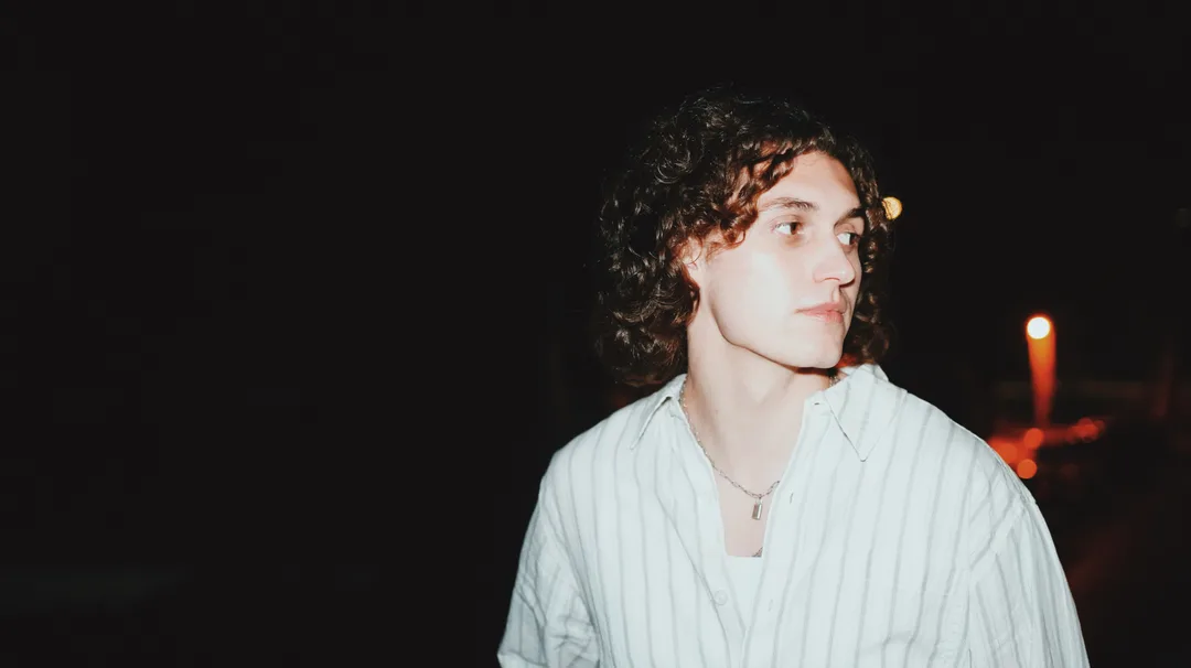Night portrait of a man in a striped shirt lit warmly against darkness